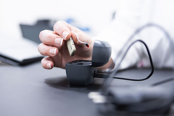 Técnico cogiendo un audífono para reparación en Centros Auditivos